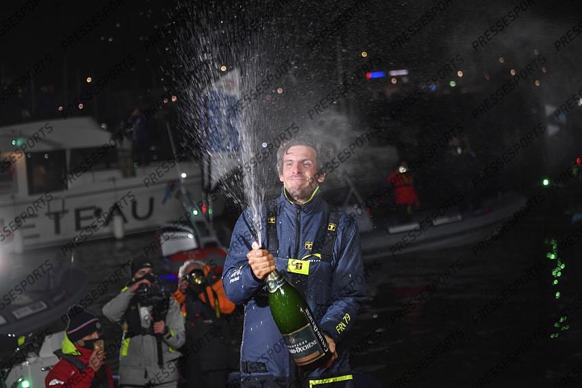 French yachtman Charlie Dalin celebrates with a bottle of champagne after crossing first the finish line of the Vendee Globe solo around-the-world sailing race, in Les Sables-d'Olonne, western France, Wednesday, Jan.27, 2021. The final winner of the race will be decided Thursday as some rival were given a time compensation. (Loic Venance, Pool via AP) 