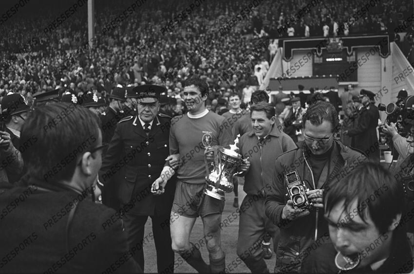 01 May 1965 FA Cup Final Leeds United v Liverpool; the injured Gordon Milne parades the trophy with Liverpool skipper Ron Yeats who is restrained by a Wembley Stadium commisionaire. Photo: Gerry Cranham. FA Cup Final 1965 