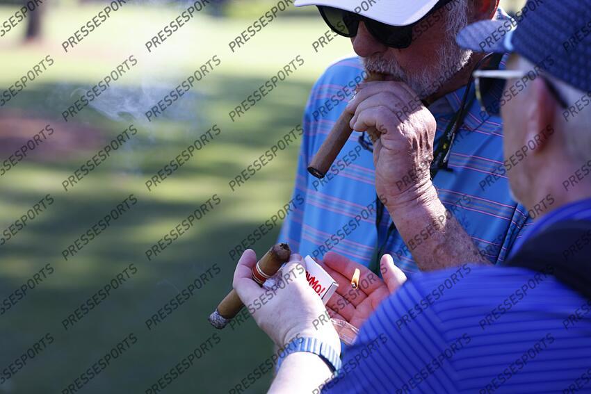 Apr 8, 2025; Augusta, Georgia, USA; Patrons light a cigar near the 11th green during a practice round for the Masters Tournament at Augusta National Golf Club. Mandatory Credit: Peter Casey-Imagn Images PGA: Masters Tournament - Practice Round 